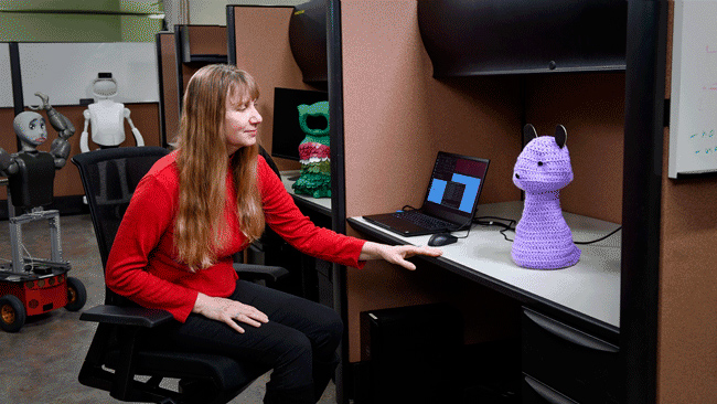Women staring at a knitted figurine 