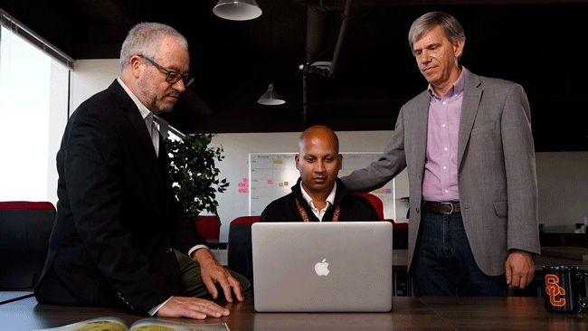 Three men standing in front of a computer